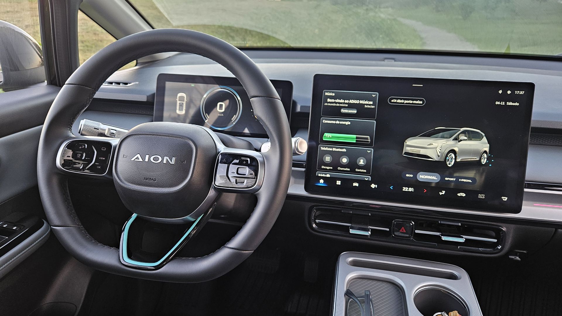 Interior do carro AION mostrando o volante e uma tela digital com informações de energia e conectividade Bluetooth.