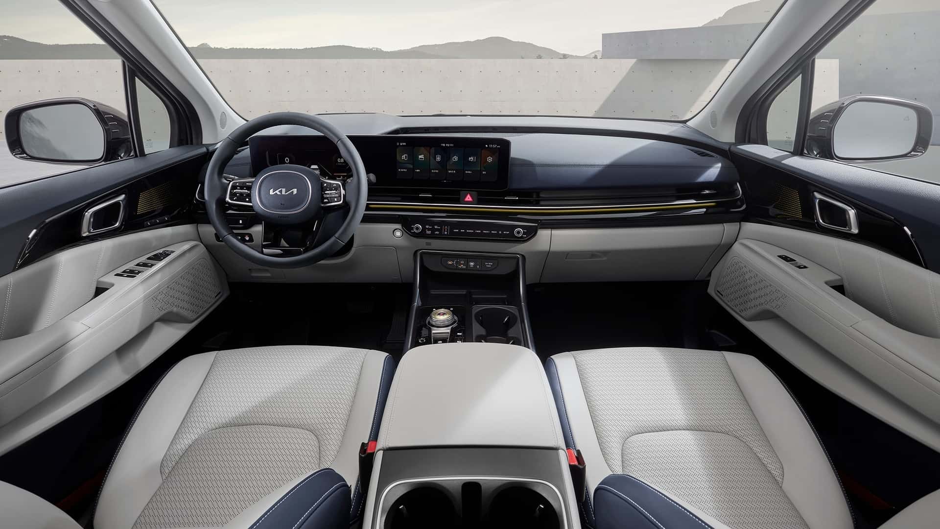 Interior moderno de um carro da Kia, com volante esportivo, painel digital e assentos em couro claro.