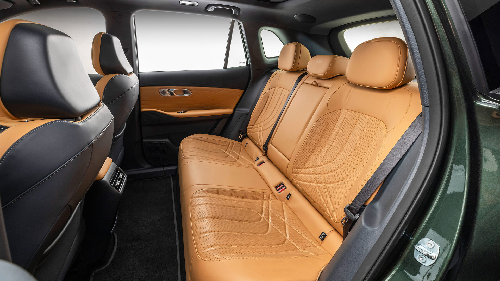 Interior traseiro de um carro com bancos de couro marrom claro e detalhes em preto.