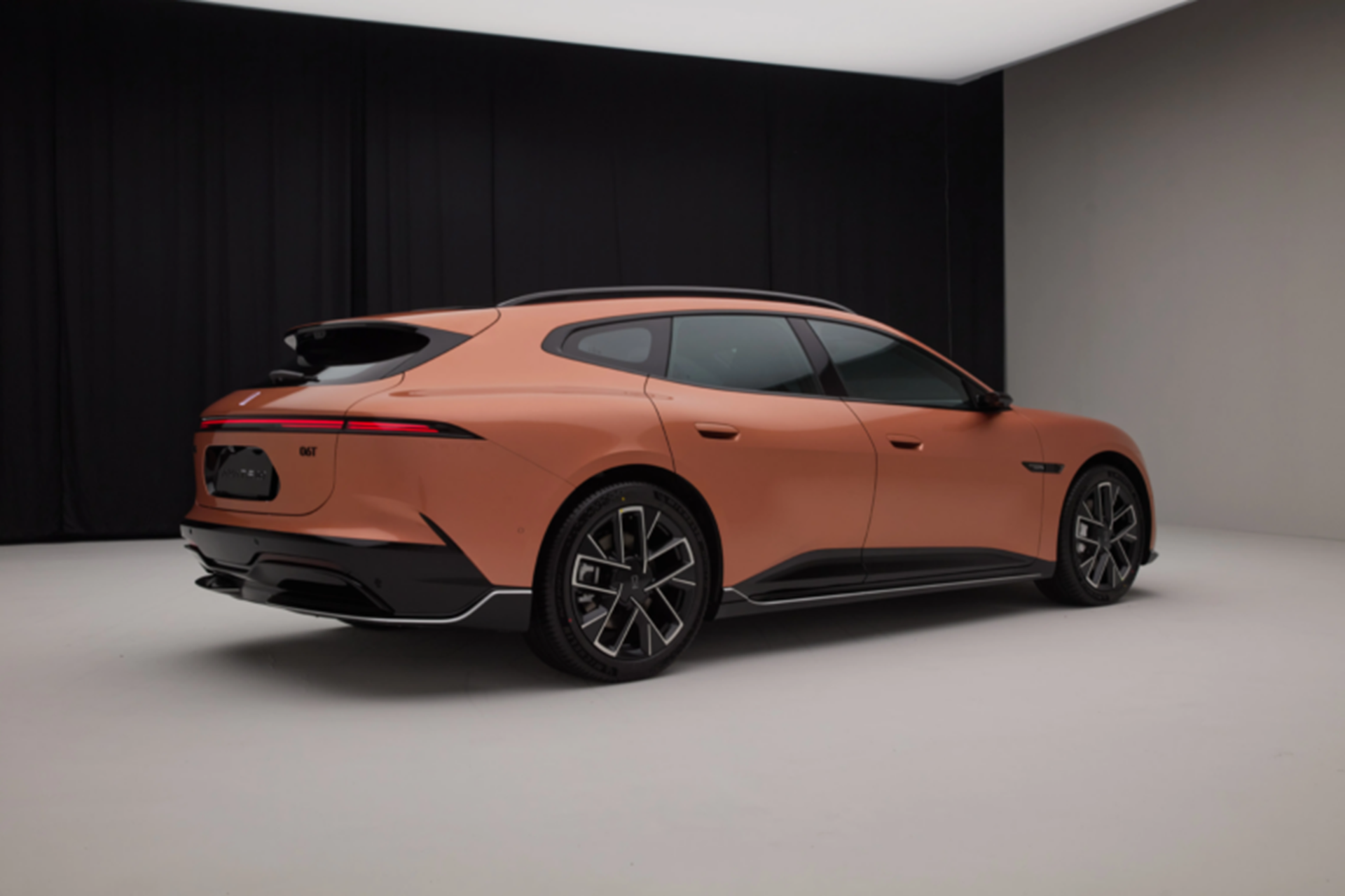 A sleek orange electric car viewed from the rear, showcasing its modern design and distinctive features.