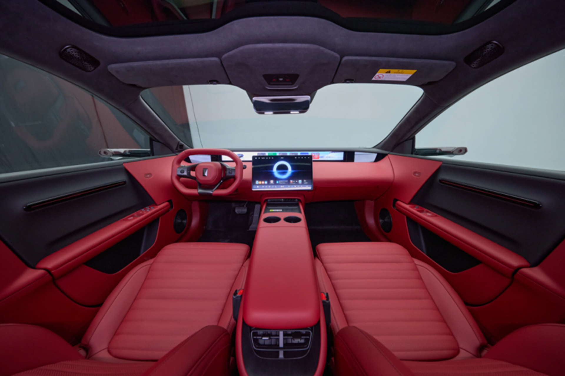View of a modern car interior featuring sleek red leather seats and a high-tech dashboard with a central touchscreen display.