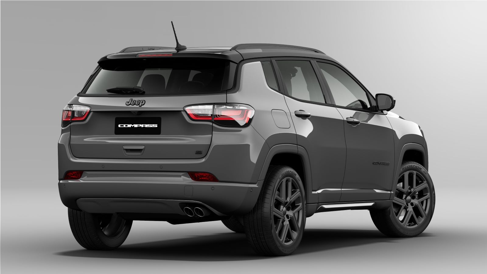 Vista traseira de um Jeep Compass cinza, destacando os faróis, o logotipo da Jeep e as rodas esportivas.
