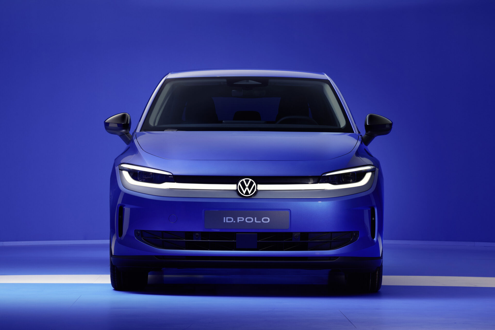 Frente do carro Volkswagen ID. Polo em destaque, com pintura azul e fundo azul liso.