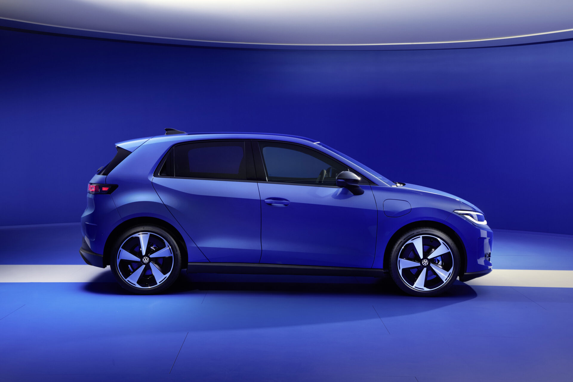 Carro azul em um fundo azul, exibindo seu perfil e rodas de design moderno.