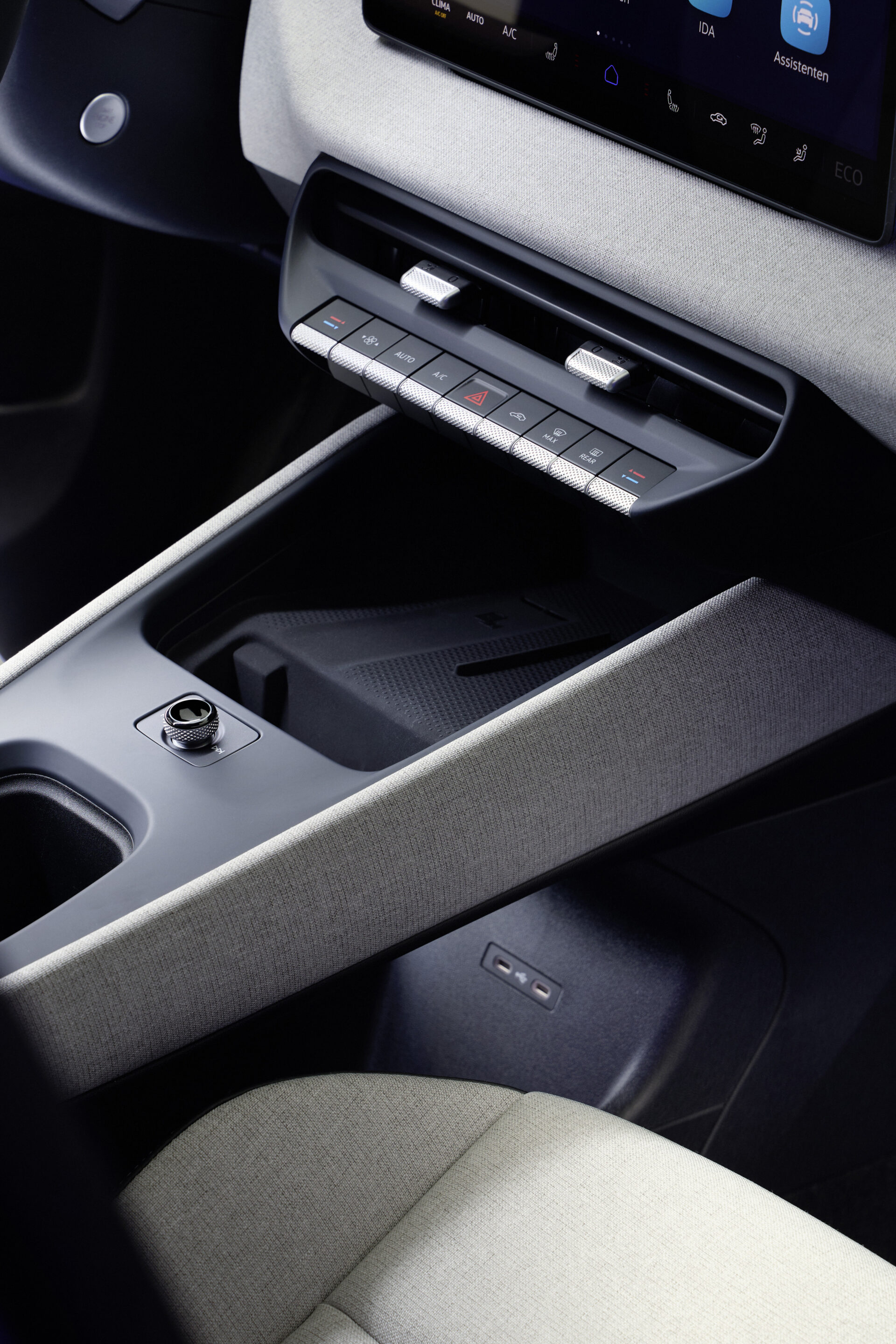 Interior de carro com console central, botões de controle de ar-condicionado e um espaço de armazenamento.
