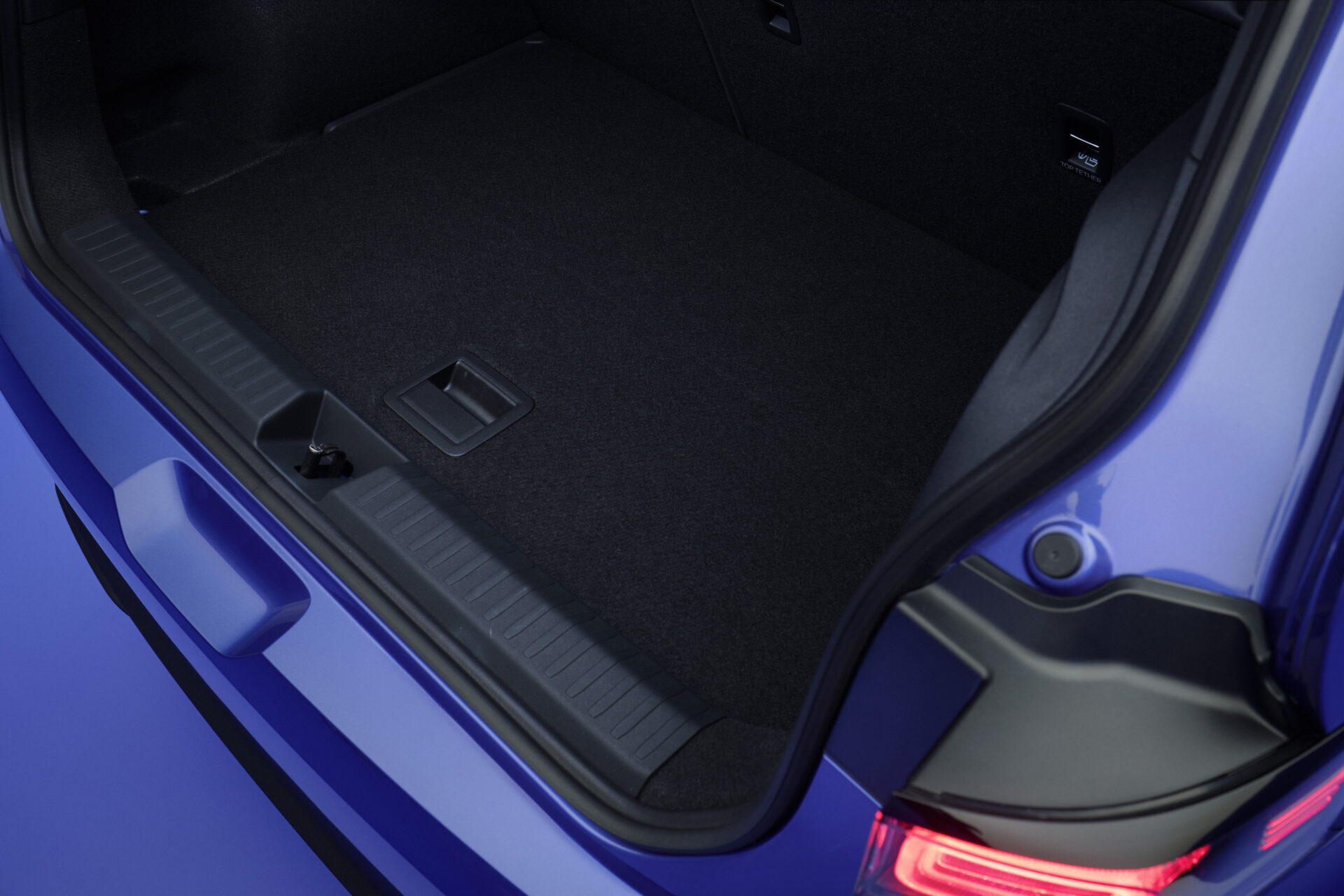 Imagem do porta-malas de um carro azul, com fundo escuro e detalhes em plástico.