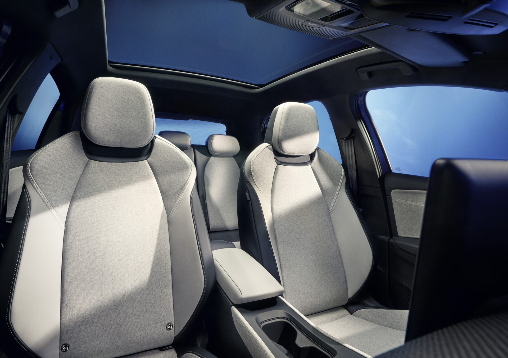 Interior de carro mostrando assentos dianteiros em tecido cinza e um console central.