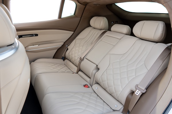 Interior de um carro mostrando os bancos traseiros em couro beje com design acolchoado.