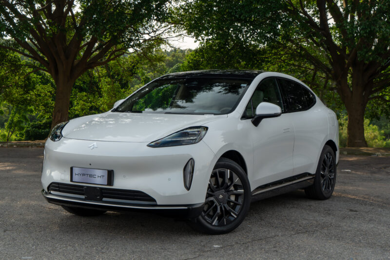 Carro SUV branco estacionado sob árvores verdes, com rodas escuras e design moderno.