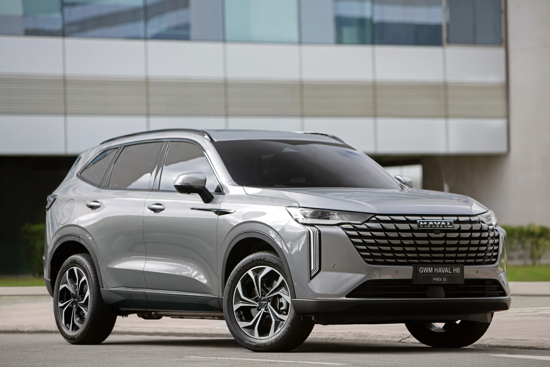 Veículo da marca Haval, modelo H6, na cor prata, estacionado em um ambiente urbano, com fundo de edifícios.