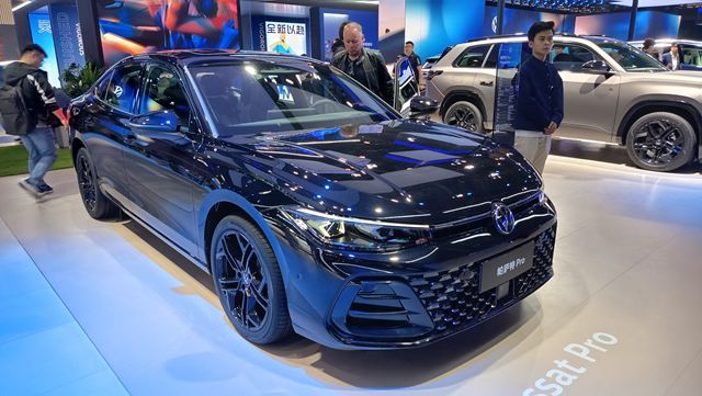 Carro preto em exibição em uma feira, com destaque para o design moderno e esportivo.