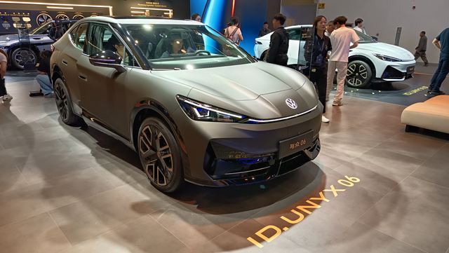 Carro elétrico Volkswagen ID. UNX 06 em um salão de automóveis, com acabamento em tom mate e design moderno.