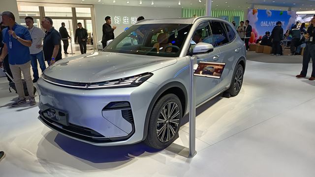 SUV elétrico prata em um evento, exibindo design moderno e rodas detalhadas.