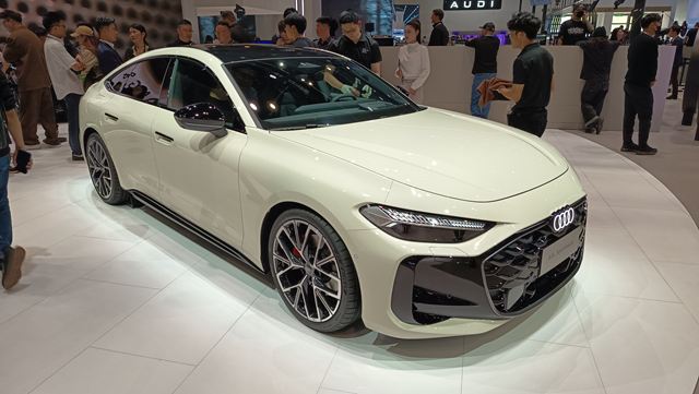 Um carro Audi A7 Sportback branco em um evento, com público ao fundo.