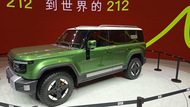 Um veículo utilitário esportivo (SUV) verde, com design robusto, exibido em um estande com fundo vermelho e o texto em chinês ao fundo.