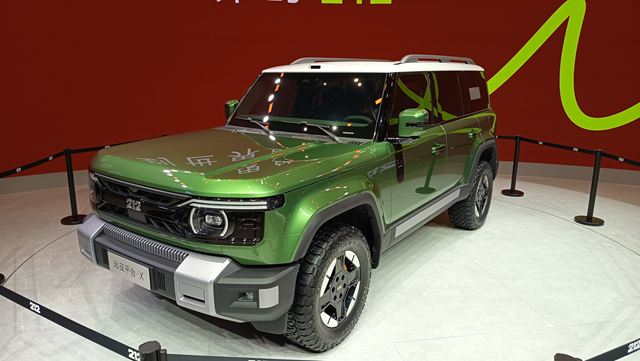 SUV verde exposta em um salão do automóvel, com detalhes de design moderno e rodas grandes.