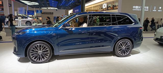 Um SUV azul metálico exibido em uma feira de automóveis, com destaque para suas rodas grandes e design moderno.