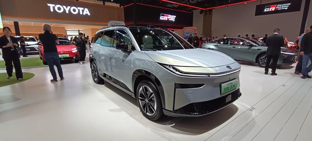 Um SUV moderno em um salão automotivo, exibindo design elegante e tecnologia avançada, com outros veículos ao fundo.