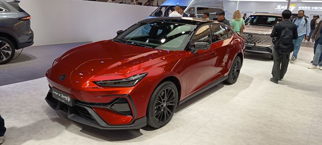 Carro vermelho esportivo em uma exposição de automóveis, exibindo um design moderno e agressivo.