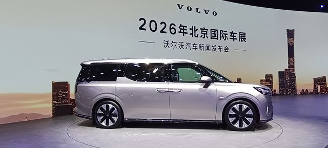 Veículo da Volvo em destaque em um evento automotivo, com uma tela de fundo apresentando o nome do evento e a data.