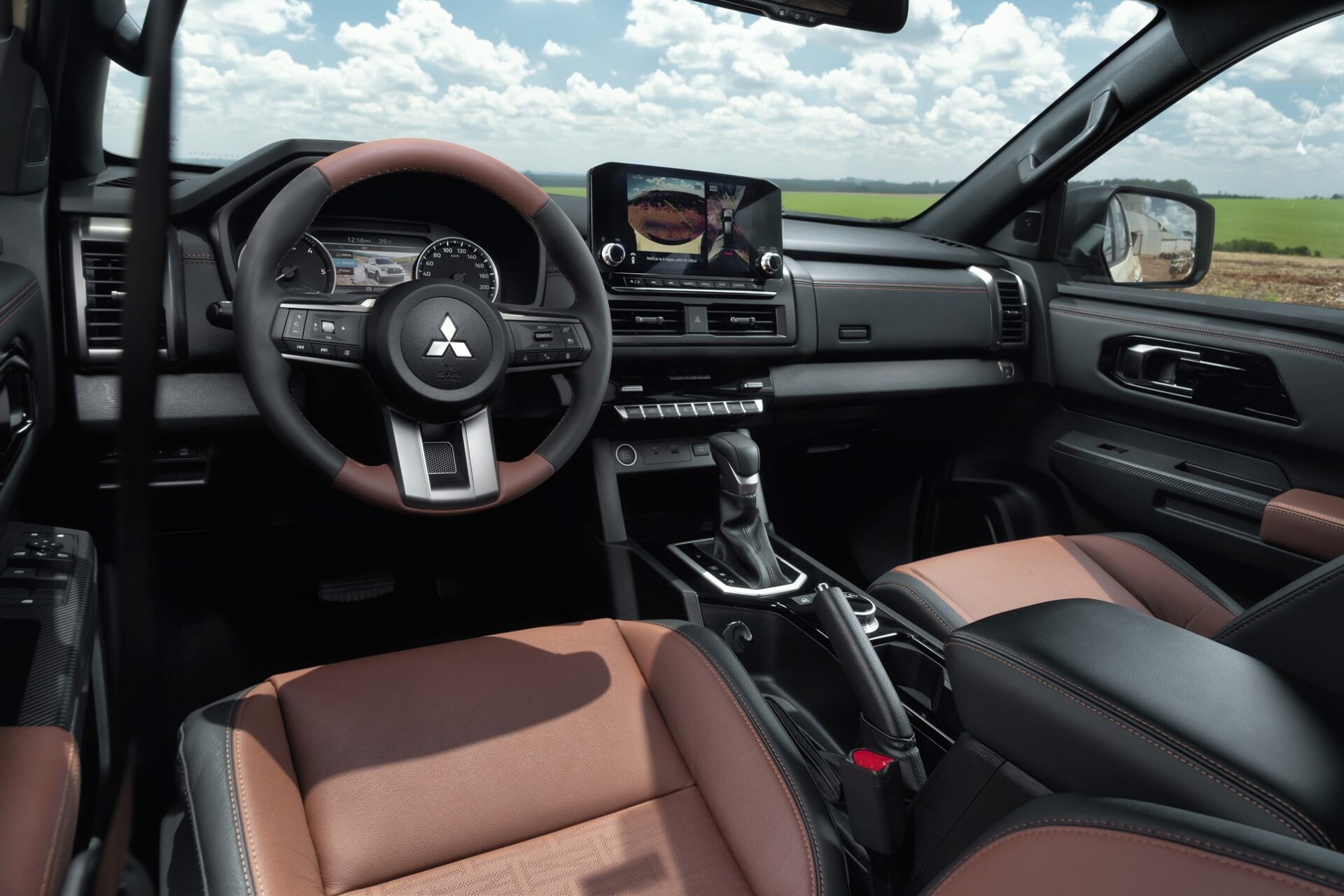 Interior view of a Mitsubishi vehicle showcasing a modern dashboard, steering wheel, touchscreen display, and leather seats with brown and black accents.