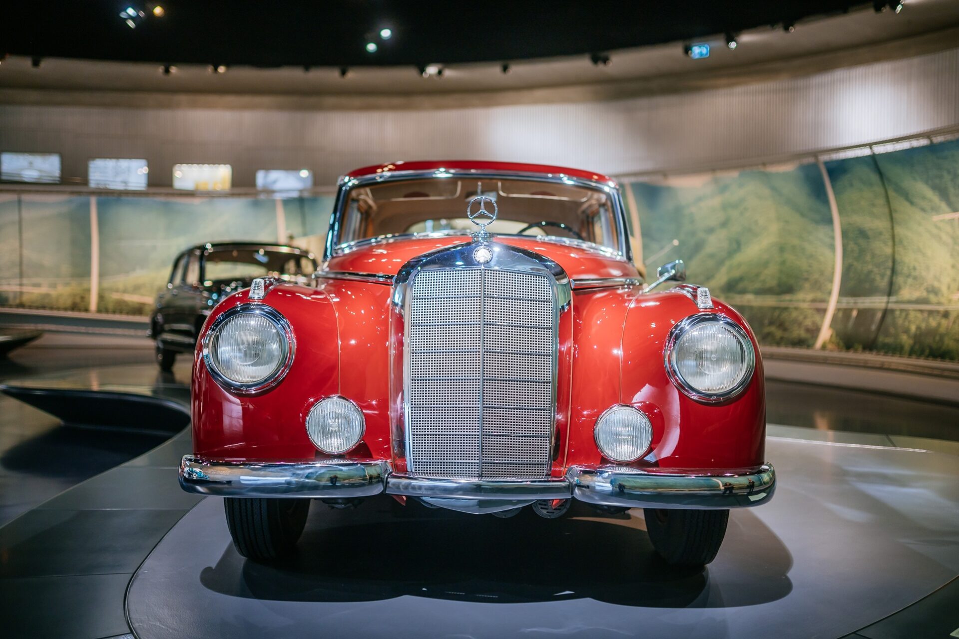 Front view of a vintage red Mercedes-Benz car displayed in a museum setting.