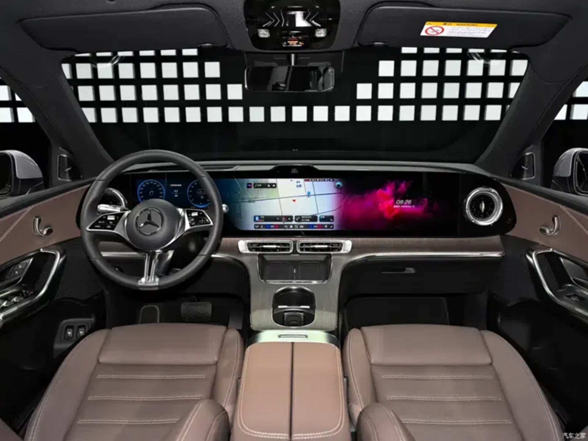 Interior view of a luxury car featuring a modern dashboard with a large touchscreen display, a stylish steering wheel, and brown leather seats.