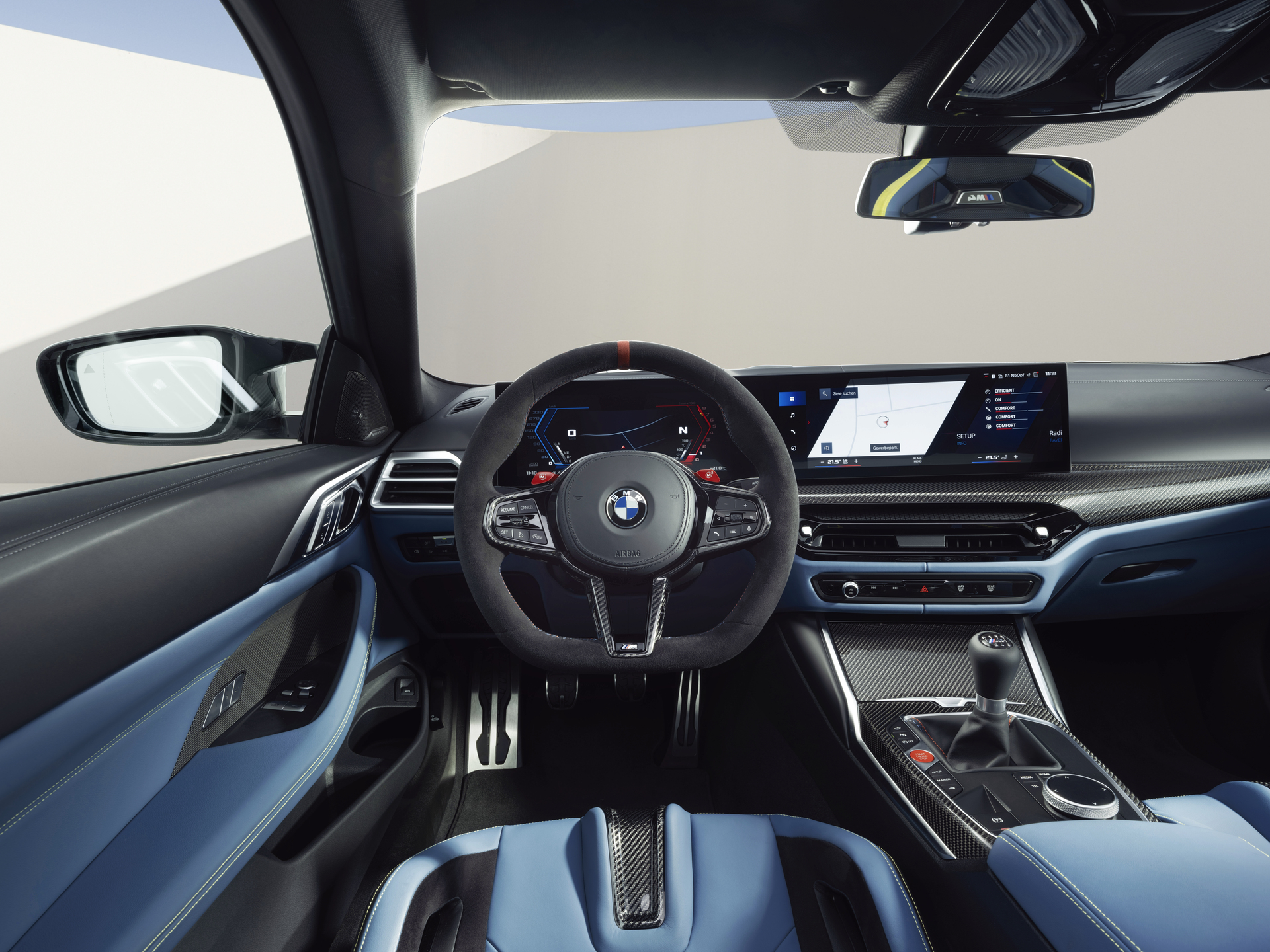 Interior de um carro BMW, exibindo o volante, painel digital e console central em tons de preto e azul.