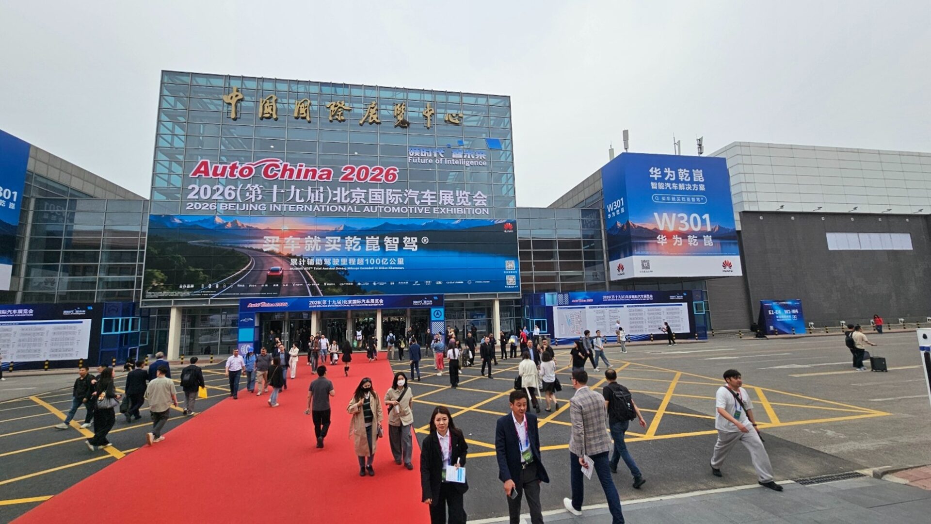 Entrance of the 2026 Beijing International Automotive Exhibition with attendees walking on a red carpet.