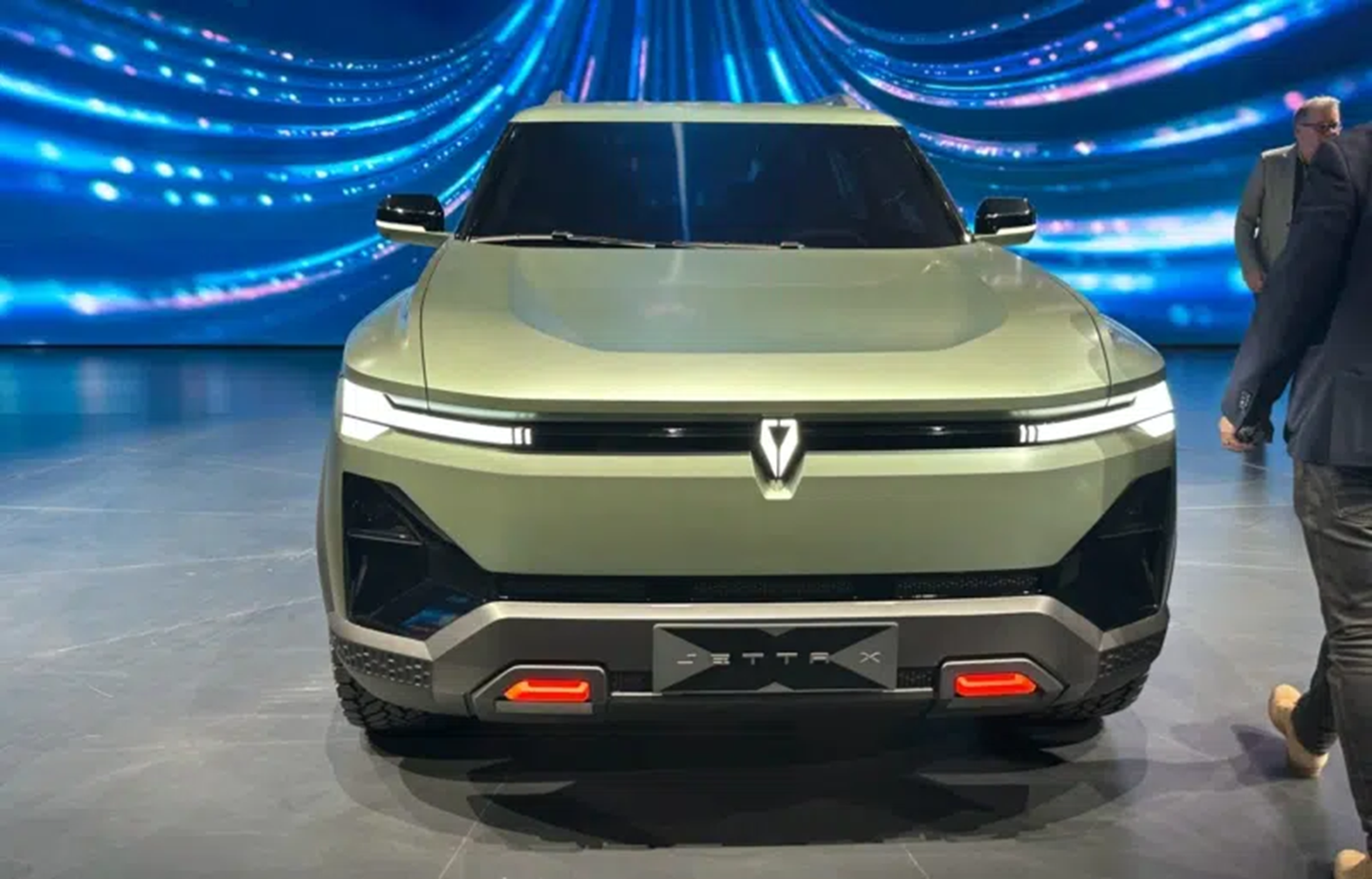 Front view of a modern SUV with a sleek design, featuring a light green color, LED headlights, and a distinctive logo on the grille.