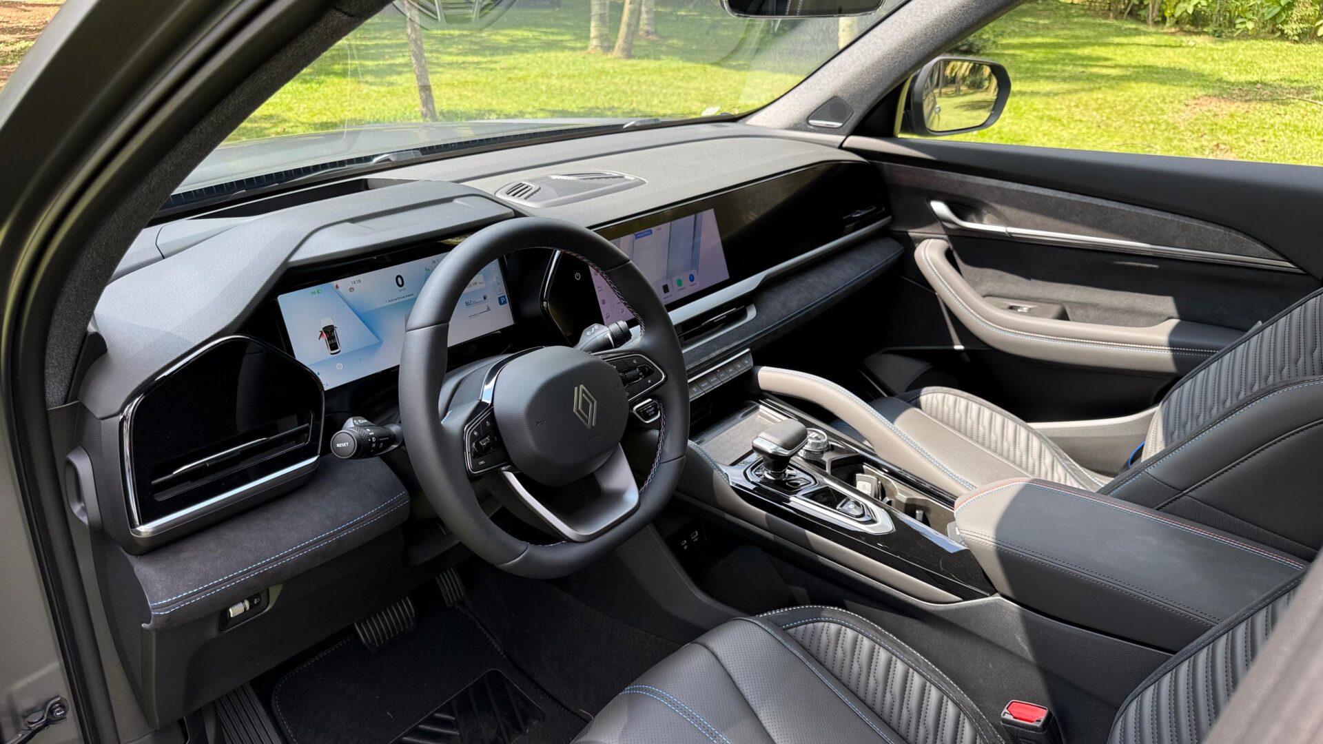 Interior de um carro moderno mostrando o volante, painel digital e bancos de couro com detalhes em costura.