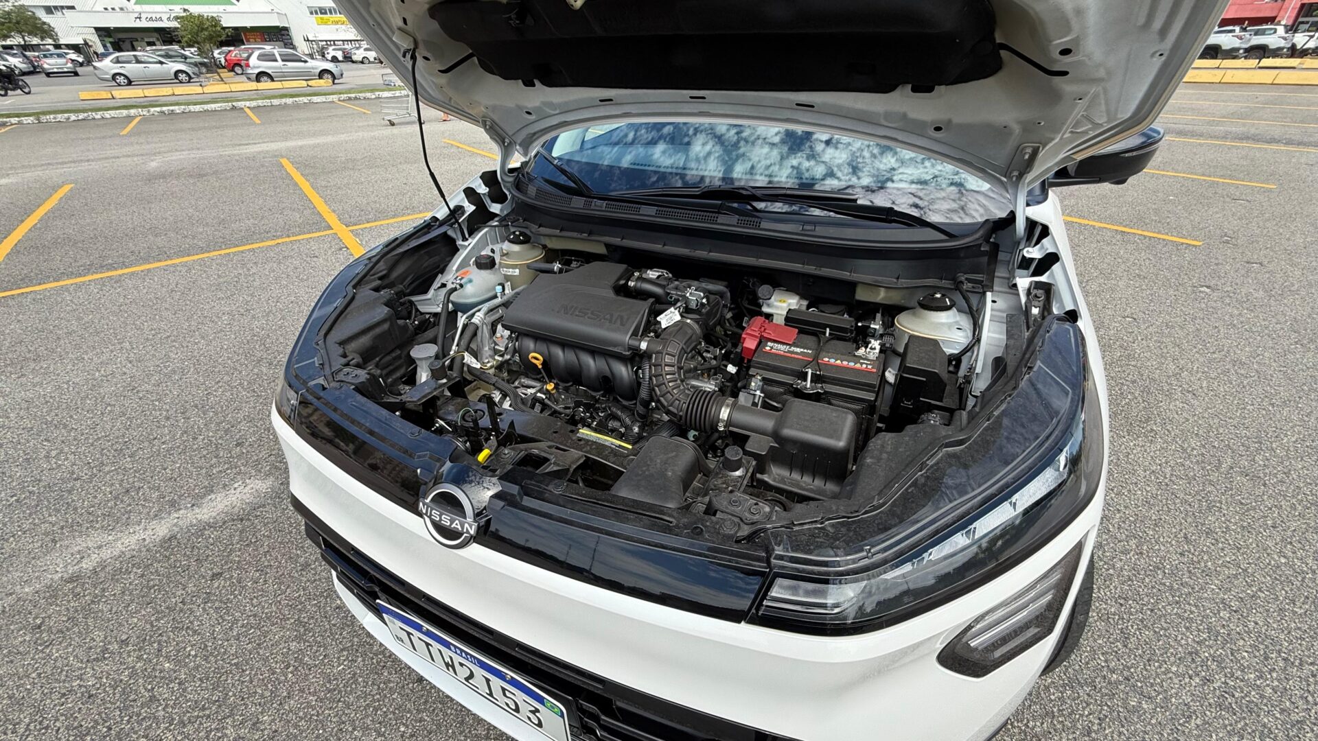 Visão do motor de um carro Nissan com o capô aberto, revelando componentes do motor e sistemas de funcionamento.