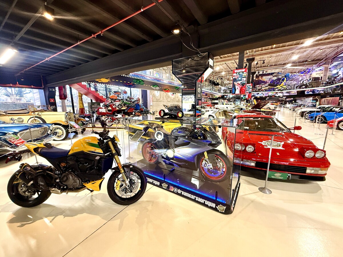 Exposição de carros clássicos e motocicletas em um museu automotivo, com veículos variados em exibição sob iluminação moderna.