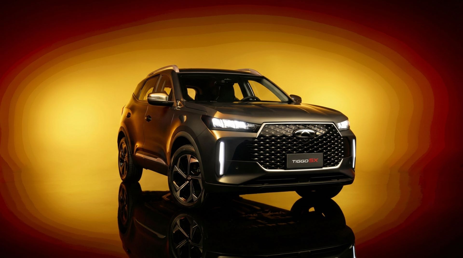 SUV Chery Tiggo 5X em destaque sobre fundo amarelo e laranja, com design moderno e elegante.