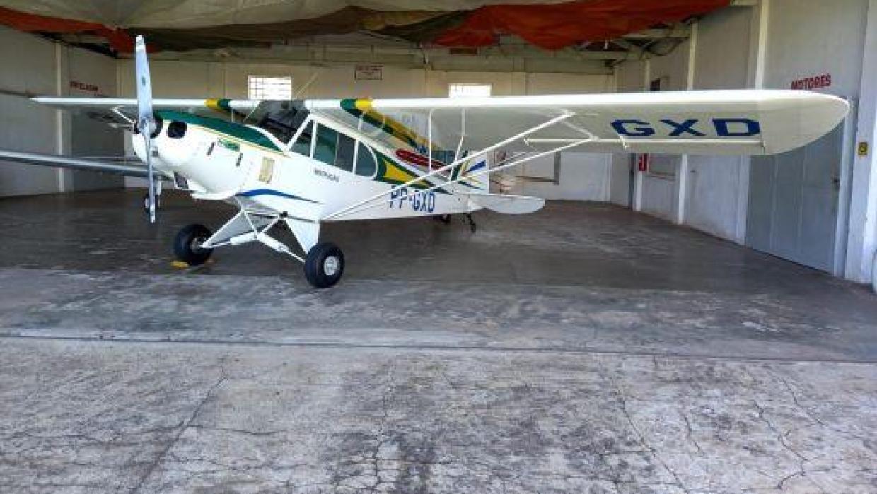 Avião monomotor estacionado em um hangar, com detalhes coloridos nas asas e fuselagem branca.