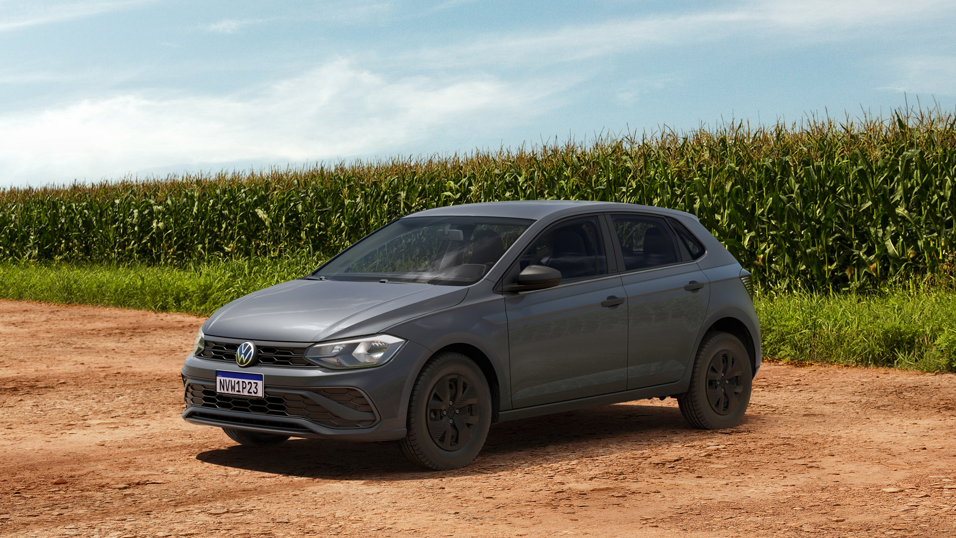 Carro Volkswagen cinza estacionado em um caminho de terra, com um campo de milho ao fundo.