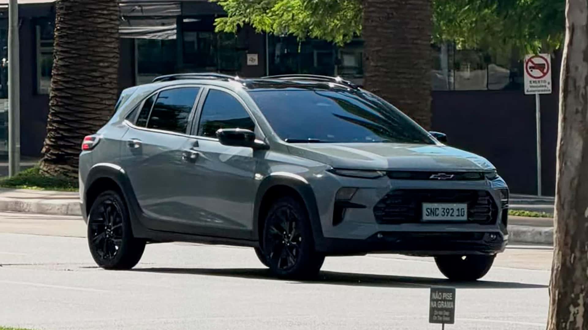 Um carro SUV cinza da Chevrolet estacionado em uma rua, com rodas pretas e reflexos na janela.