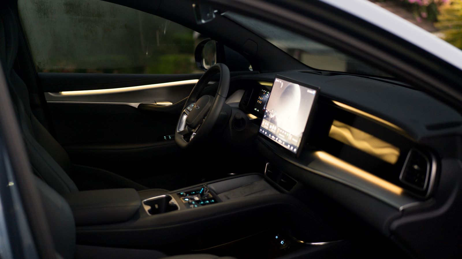 Interior de um carro moderno com volante, painel digital e iluminação suave.