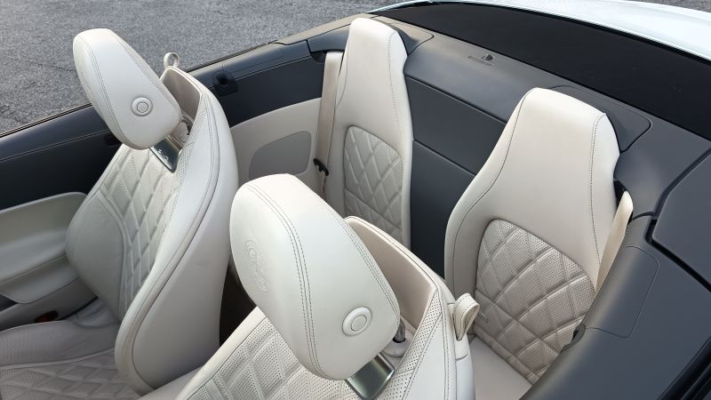 Interior de um carro conversível com assentos de couro branco e detalhes em quilt.