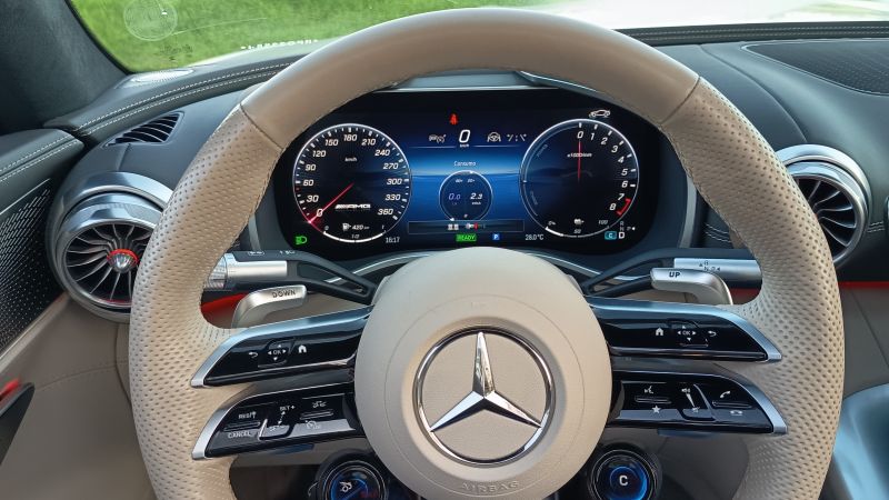 Painel de controle de um carro esportivo Mercedes-Benz, mostrando o velocímetro, termômetro e vários indicadores, com volante revestido em couro claro.