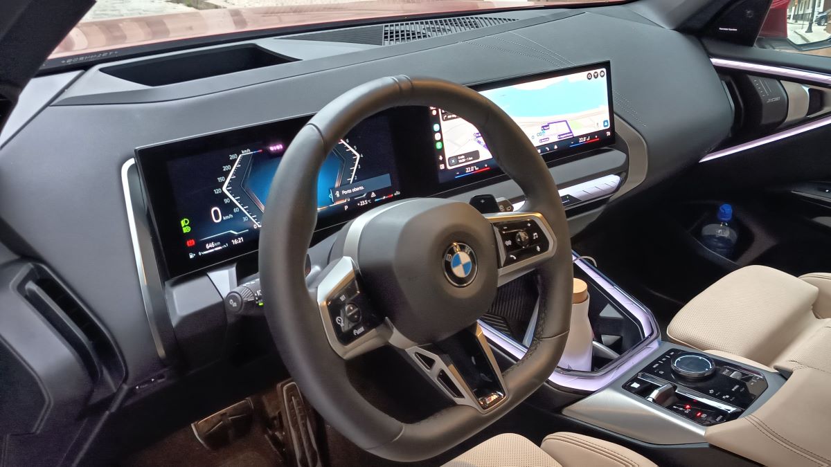 Interior de um carro BMW, com volante, painéis digitais e console central.