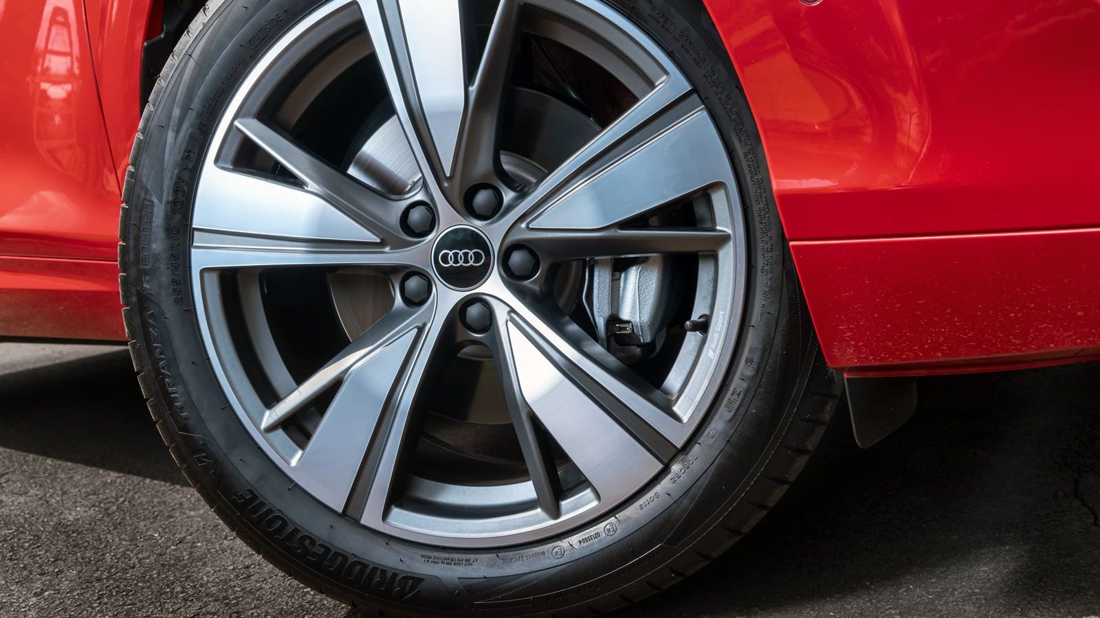 Detalhe da roda de um carro Audi vermelho, com aro prateado e pneu Bridgestone.