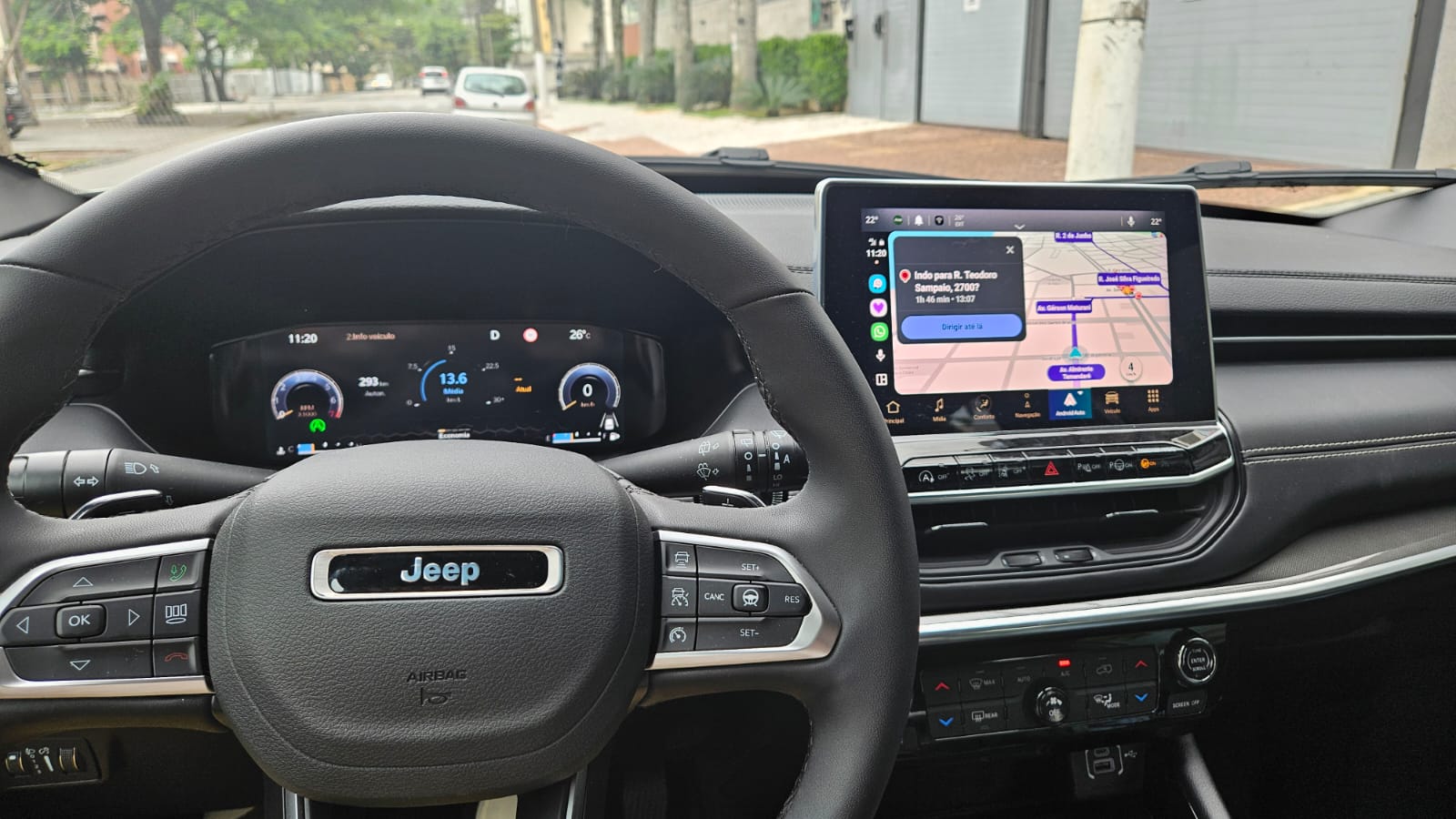 Interior de um carro Jeep, mostrando o volante e a tela do painel com informações de navegação e desempenho.