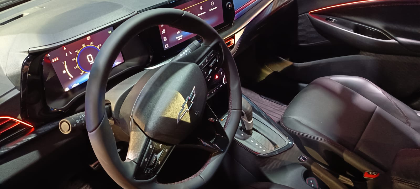 Interior de carro moderno com volante, painel digital e bancos em couro.