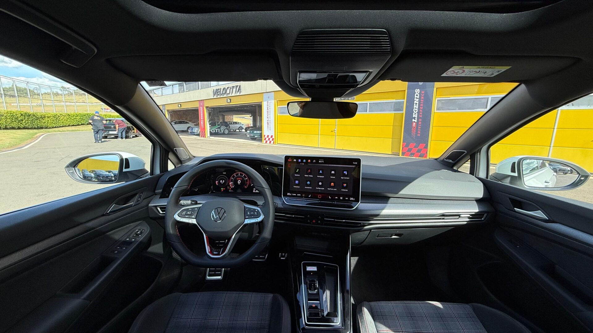 Interior do carro Volkswagen com volante, painel digital e tela de infotainment, vista do lado do motorista.