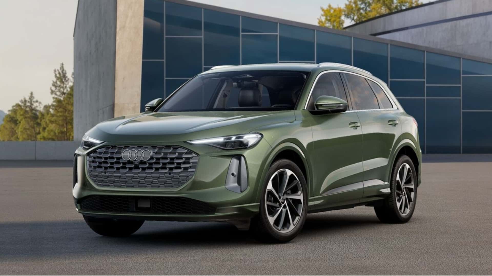 SUV Audi de cor verde estacionado em frente a um edifício moderno.