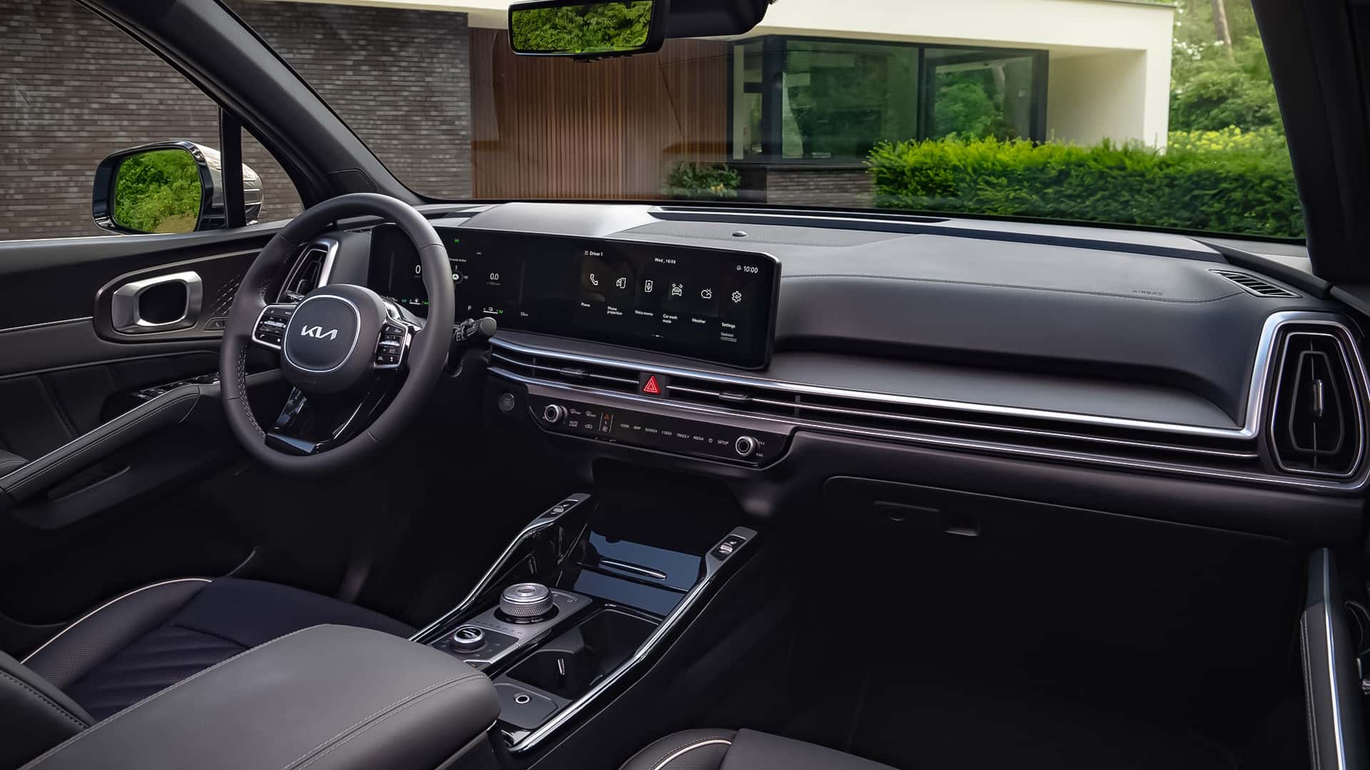 Interior de um carro moderno, destacando o volante com o logo da Kia, painel digital e console central sofisticado.