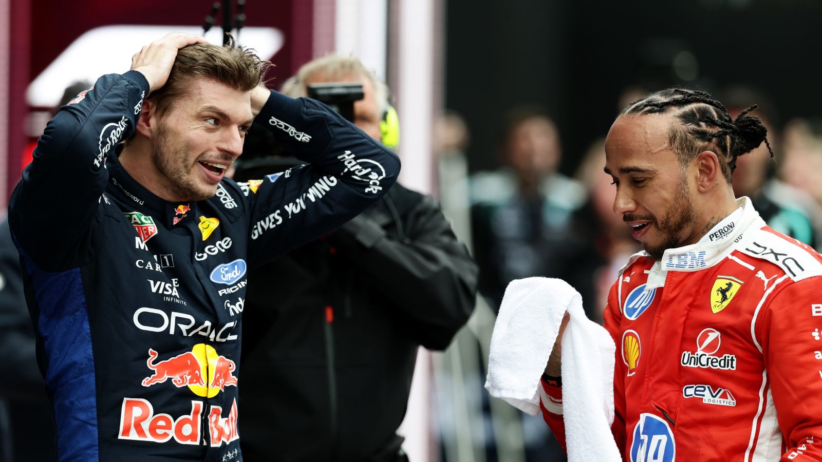 Dois pilotos de Fórmula 1 conversam após uma corrida, um deles com camisa da Red Bull e o outro da Ferrari.