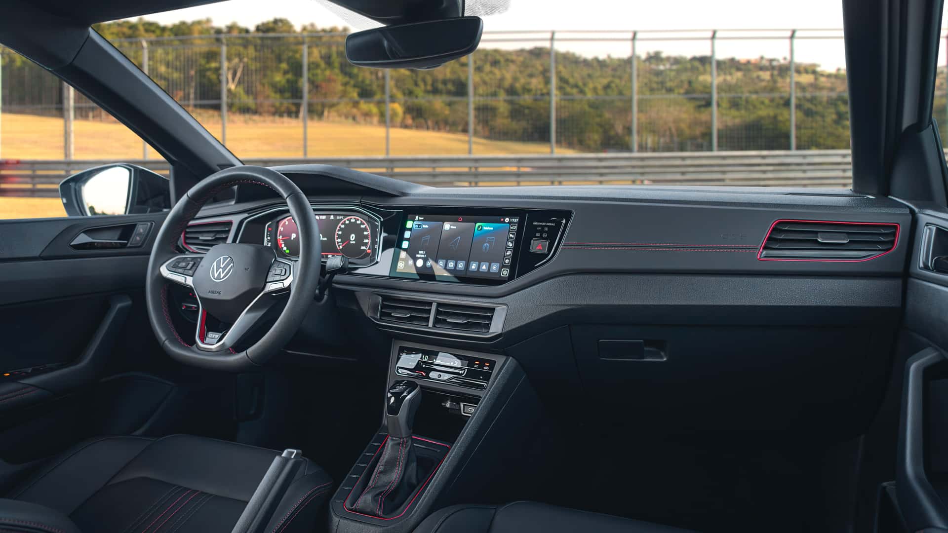 Vista interna do carro Volkswagen, destacando o volante, painel de instrumentos digital e sistema de infoentretenimento.