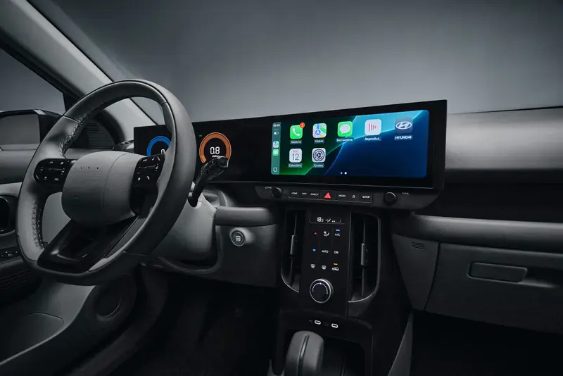 Interior de um carro mostrando o volante e um painel digital moderno com telas para informações e conectividade.